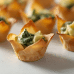 Close‑up Spinach & Artichoke Wonton Cups with garlic specks​