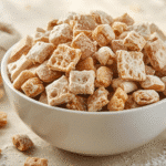 Serving bowl of Caramel Apple Puppy Chow featuring mix-ins like mini pretzels and roasted peanuts, showcasing a perfect blend of textures and harvest flavors.