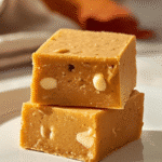 Alt Text: Macro close-up of a single bite taken out of a White Chocolate Pumpkin Fudge square, revealing its soft, non-grainy consistency.