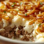 Close-up of cheesy French onion beef rice bake in a white ceramic dish.
