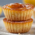 Golden baby lemon impossible mini pies styled as afternoon tea party snacks on a white ceramic plate with a dusting of sugar.