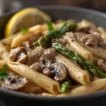 Homemade Mushroom Asparagus Chicken Penne served in a white ceramic bowl on a marble surface.
